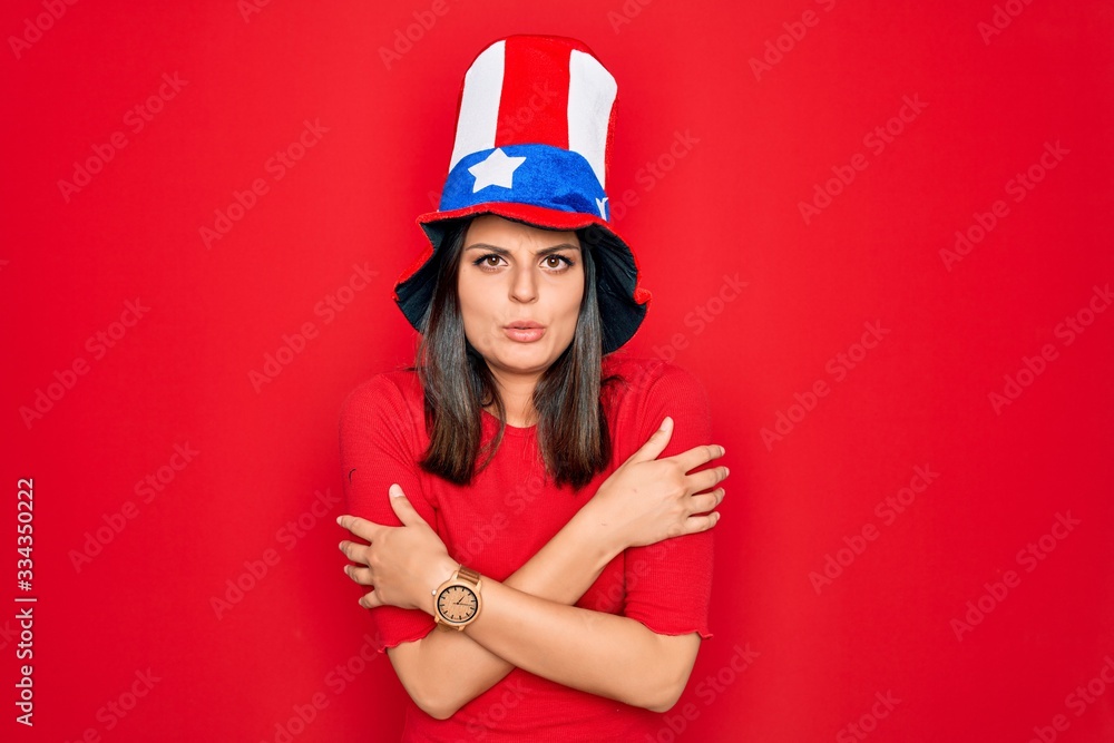 Young beautiful brunette woman wearing united states hat celebrating independence day shaking and freezing for winter cold with sad and shock expression on face Young beautiful brunette woman wearing united states hat celebrating independence day shaking and freezing for winter cold with sad and shock expression on face