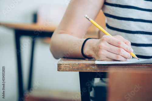 high school university student study.hands holding pencil writing paper answer sheet.sitting lecture chair taking final exam attending in examination classroom.concept scholarship for education abroad