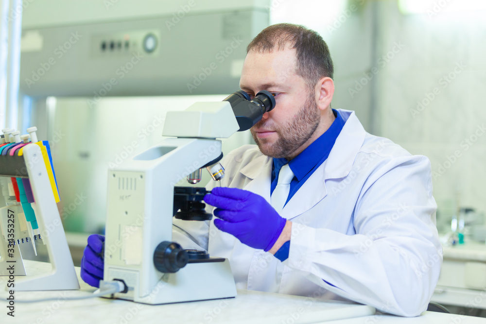 Specialist looking through microscope performing scientific research in a laboratory Specialist looking through microscope performing scientific research in a laboratory