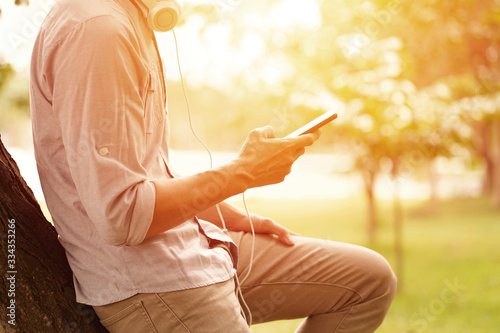 a Man listening to a music from a smartphone with garden background