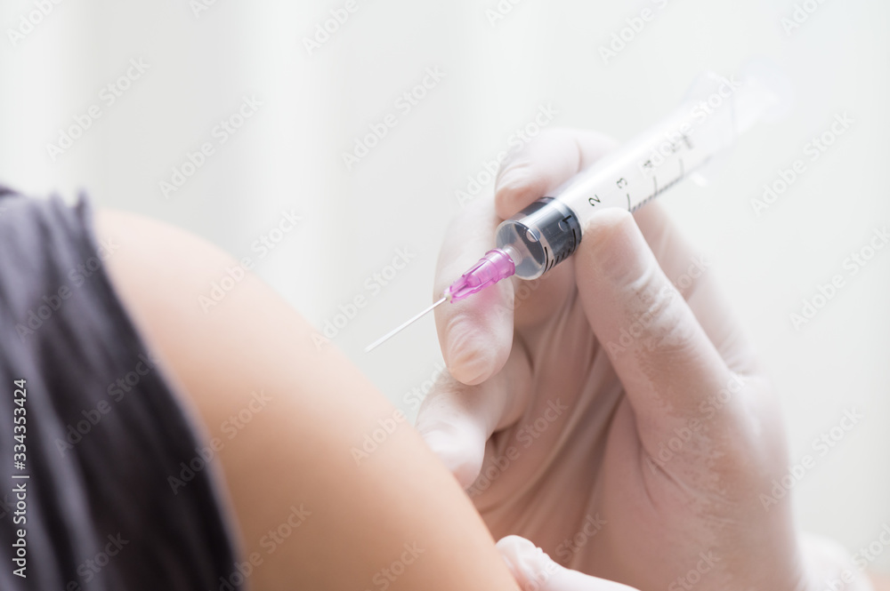 close up doctor's hand injecting for vaccination in the shoulder woman patient.Vaccine for protection HPV (Human Papillomavirus) infection.Vaccination for coronavirus treatment. close up doctor's hand injecting for vaccination in the shoulder woman patient.Vaccine for protection HPV (Human Papillomavirus) infection.Vaccination for coronavirus treatment.
