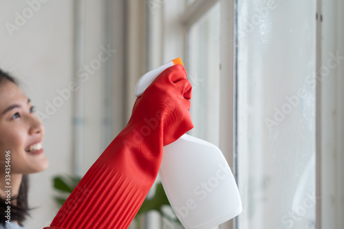 Housekeeper cleaning home concept. Woman spraying cleanser to window. photo