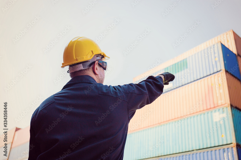Worker man in hardhat and safety vest point to the sky, Foreman control loading containers box from cargo Worker man in hardhat and safety vest point to the sky, Foreman control loading containers box from cargo