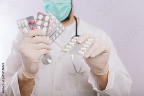 Doctor's hands in white gloves hold pills close-up. Types of drugs. Medical worker in a white coat