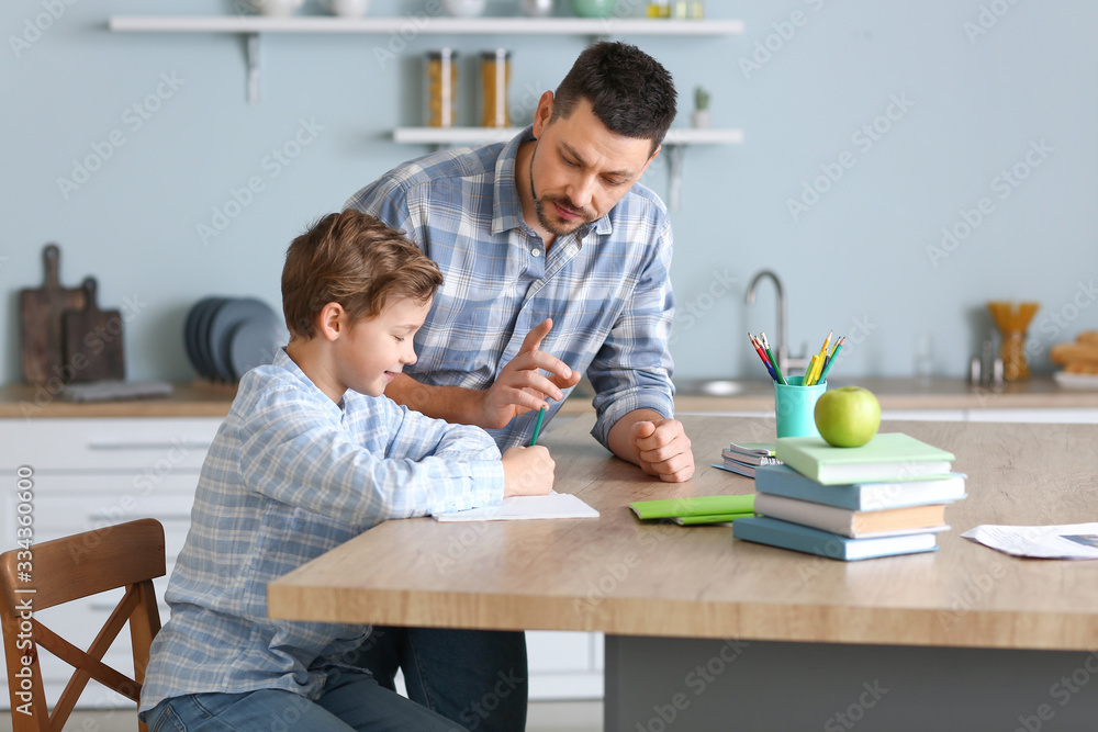 Father helping his little son to do lessons at home Father helping his little son to do lessons at home