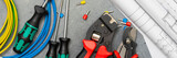 Tools and tips of various sizes and colors for crimping stranded electrical wires. Crimping tools, wire tips and electrical cable on a gray concrete background. Banner