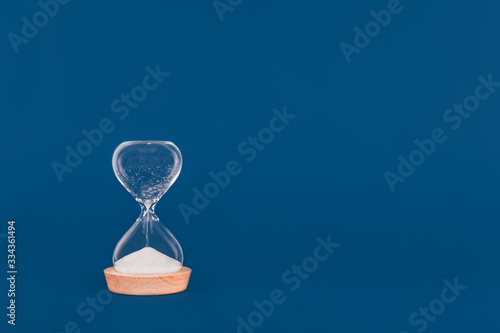 Hourglass with the last drops of sand. Concept of time and timely actions, closing opportunities. Place for text