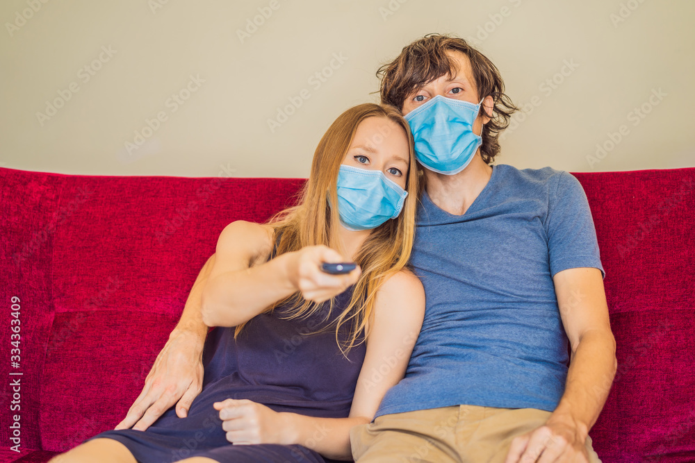 Man and woman are sitting in quarantine, sitting at home and watching TV. Coronavirus, epidemic, quarantine