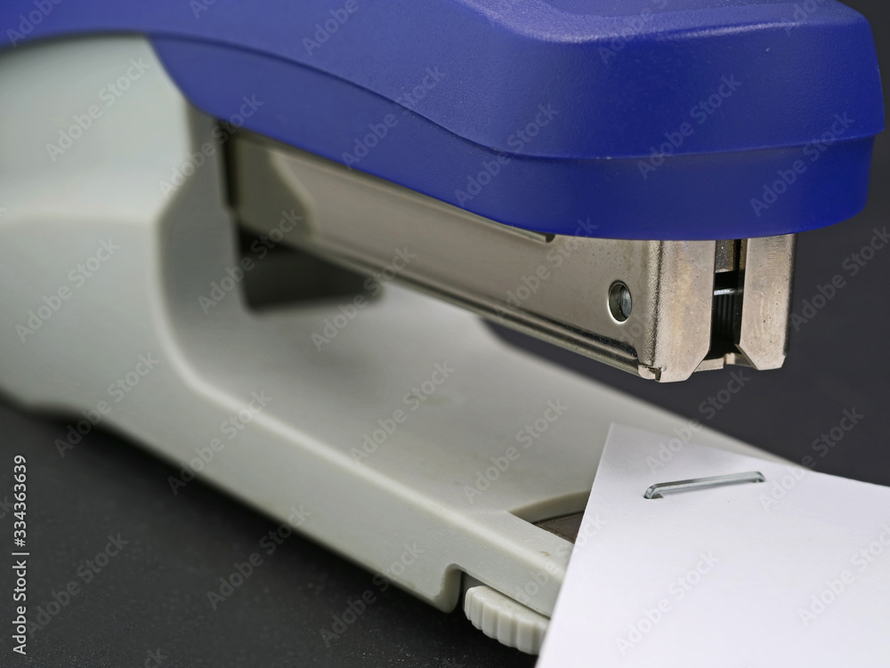 close up of blue stapler with stapled paper close up of blue stapler with stapled paper