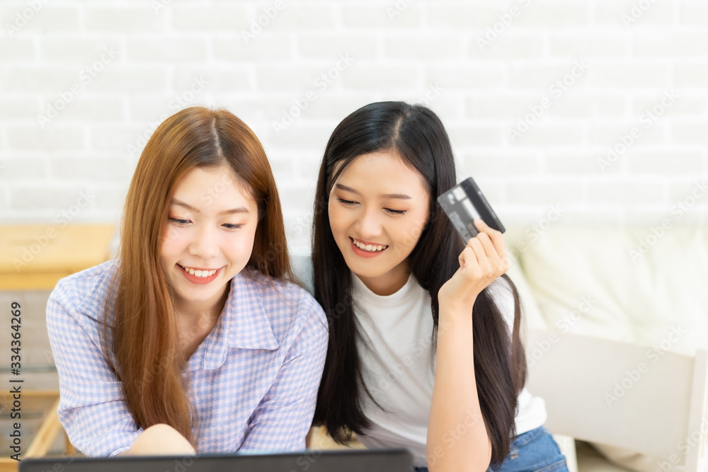 Happy best friends laughing during watching funny videos on internet social media life . Young Asian female doing online shopping through laptop and credit card at home. Happy best friends laughing during watching funny videos on internet social media life . Young Asian female doing online shopping through laptop and credit card at home.