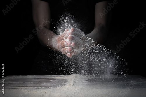White flour flies from the hands  in air on black background 