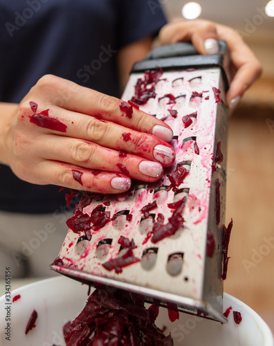 Girl cuts boiled red beets on a grater