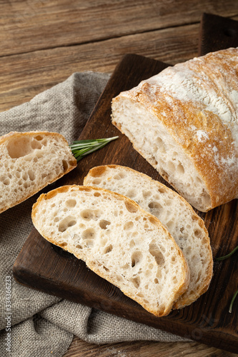 Delicious homemade sliced Italian ciabatta bread on a wooden cutting board. Close-up.