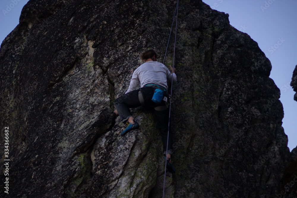 A man is climbing outdoors with safety rope A man is climbing outdoors with safety rope