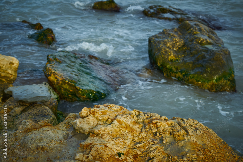 Rocky seashore. Sea waves roll over stones.