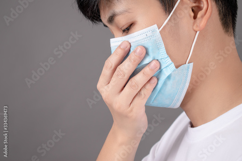 Asian people wear white shirts and wear masks while coughing on a gray background. With copy area, side view. Health care concept.