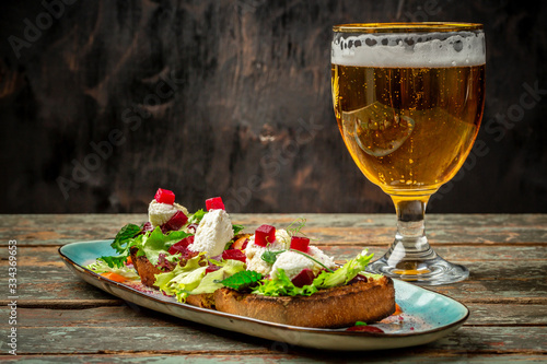 Hearty snack with different kinds of spreads on farmhouse bread served with a fresh yeast wheat beer on an old wooden table