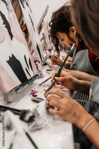 Young women paint with brushes on easels in art class. art school, creativity and people concept photo