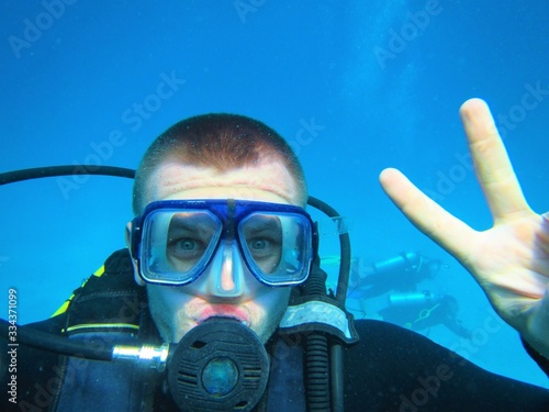Close-up of a young man underwater in diving equipment, who is engaged in diving.