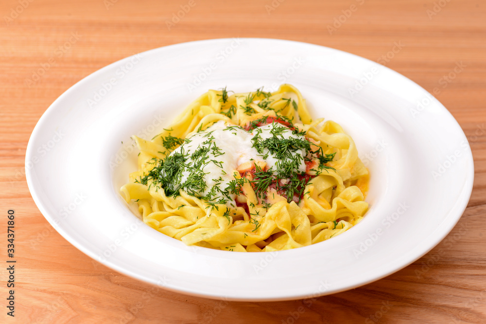 Spaghetti pasta with dill and tomato sauce served in white plate over light rustic wooden table. Spaghetti pasta with dill and tomato sauce served in white plate over light rustic wooden table.