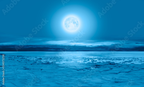 Night sky with full moon in the clouds  - Ice on the ocean shore at night  Elements of this image furnished by NASA 