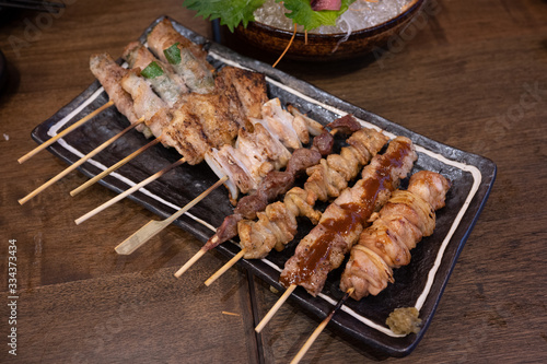 The various parts of the chicken skewers then grilled in Japanese, called Yakitori, are a popular Japanese food in the izakaya restaurant. On the dark brown wooden table.