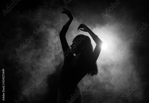 Female silhouette dancing in shadow and smoke photo