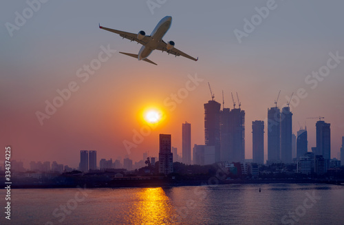 Mumbai is the financial and entertainment capital of India with airplane - Construction crane and skyscraper at sunset