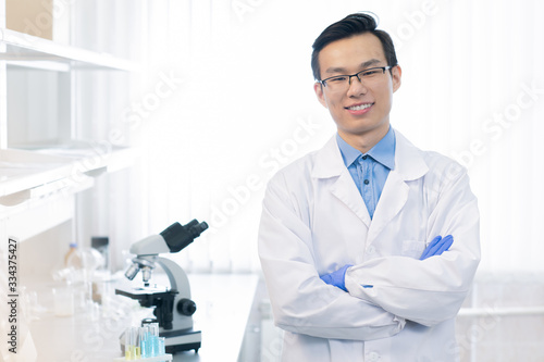 Happy young Chinese chemist or reseacher with arms crossed by chest