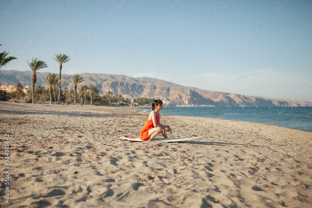 Young woman in the beach with her surf table waiting in the sand Young woman in the beach with her surf table waiting in the sand