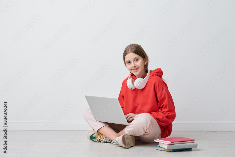 Happy teenage girl looking at you while studying in the net in isolation Happy teenage girl looking at you while studying in the net in isolation