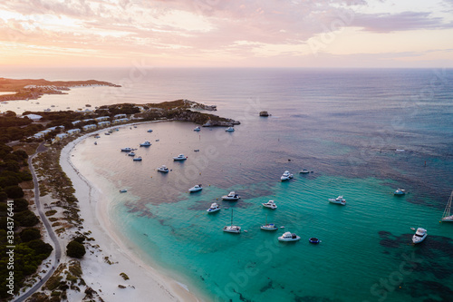 Aerial drone shot of a magical sunset over Rottnest Island, Perth, Western Australia. Geordie Bay below with luxury boats and yachts. 