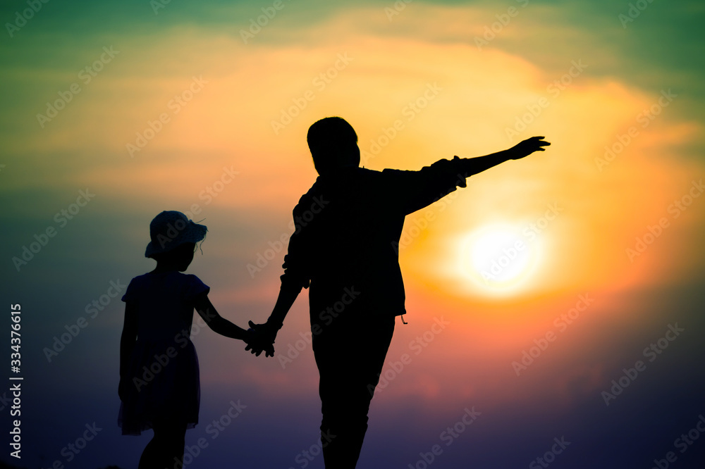 silhouette of a family with a happy mother playing with a girl in the sunset sky