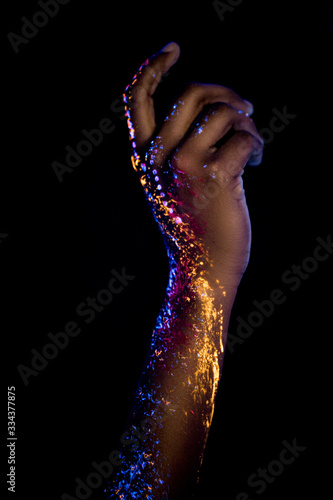 close-up photo of sensual female hands with fluorescent prints glowing on neon lights. isolated black background