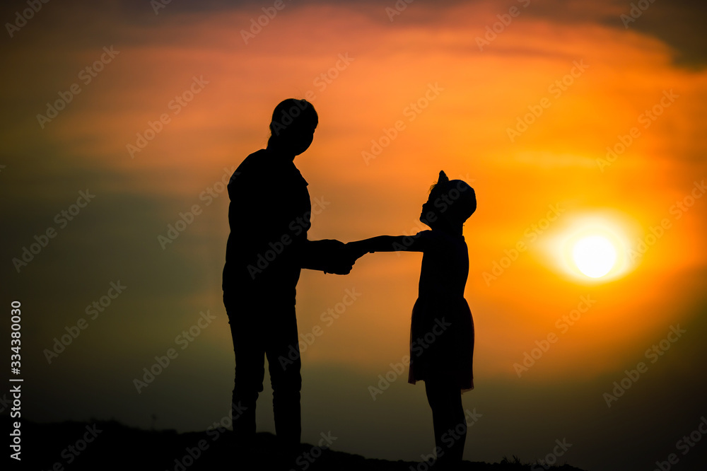 silhouette of a family with a happy mother playing with a girl in the sunset sky