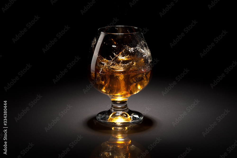 Ice cube fall and splash in beautiful glass goblet