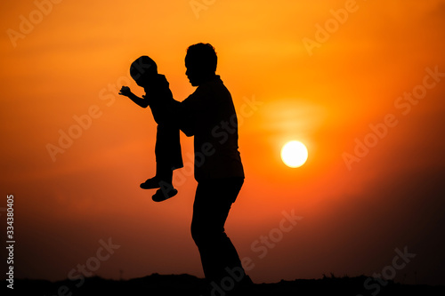 silhouette of the family that the father is playing with the boy happily with the sunset sky