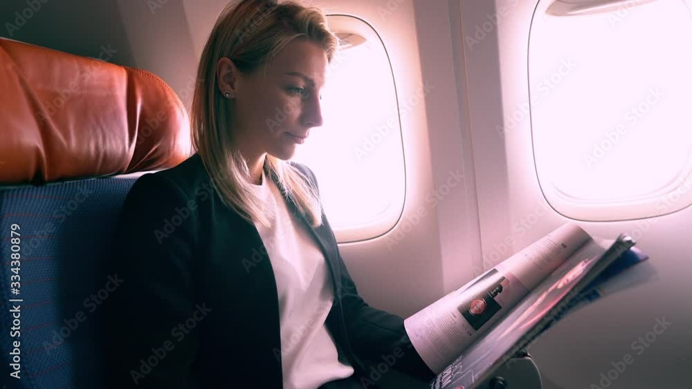 Successful woman in formal wear reading interesting article from airplane magazine during commercial departure in jet liner, confident female corporate director having business trip in airplane Successful woman in formal wear reading interesting article from airplane magazine during commercial departure in jet liner, confident female corporate director having business trip in airplane