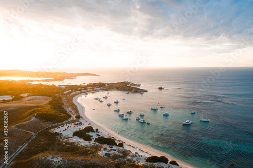 Aerial drone shot of a magical sunset over Rottnest Island, Perth, Western Australia. Geordie Bay below with luxury boats and yachts. 