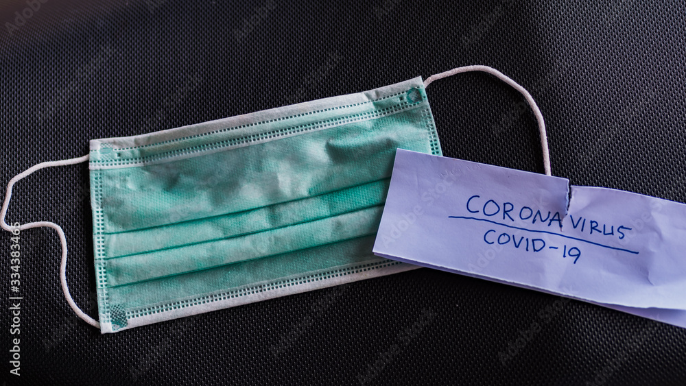 Used surgical mask and paper that read coronavirus, covid-19. This is to illustrate the scarcity of medical equipment when a corona virus disease outbreak caused a worldwide crisis. Used surgical mask and paper that read coronavirus, covid-19. This is to illustrate the scarcity of medical equipment when a corona virus disease outbreak caused a worldwide crisis.