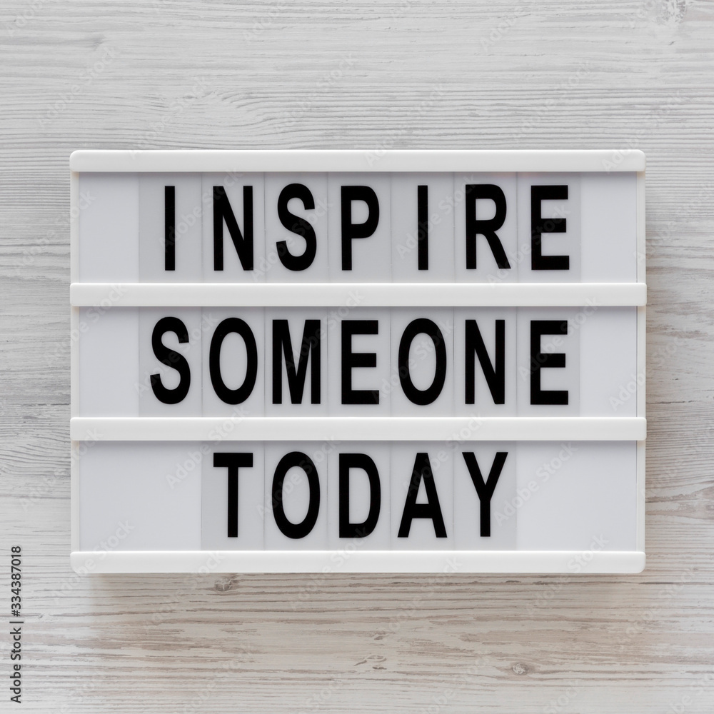 'Inspire someone today' words on a lightbox on a white wooden surface, top view. Overhead, from above, flat lay. 'Inspire someone today' words on a lightbox on a white wooden surface, top view. Overhead, from above, flat lay.