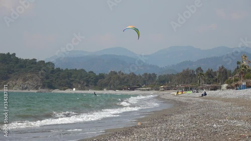 Fethiye, Turkey - 27th of Martch 2020: 4K Viewing kitesurfers riding and rolling in the wind on the beach
 photo