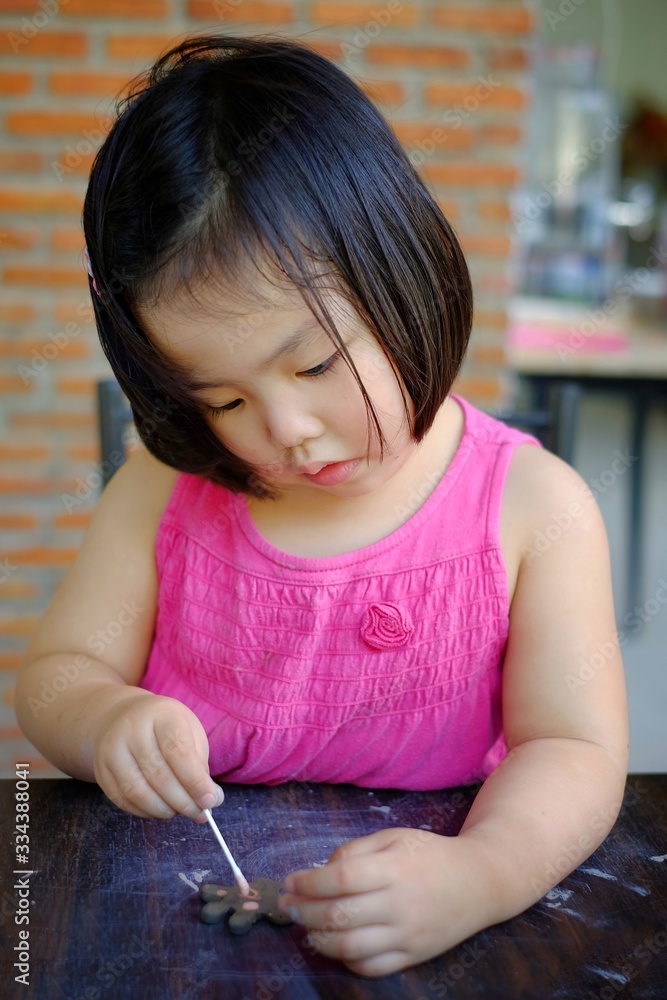 A cute Asian girl in a pottery class, painting her molded animals before baking. A cute Asian girl in a pottery class, painting her molded animals before baking.
