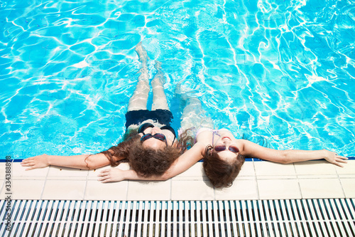 Two young women enjoying a swimming pool. Resort  spa