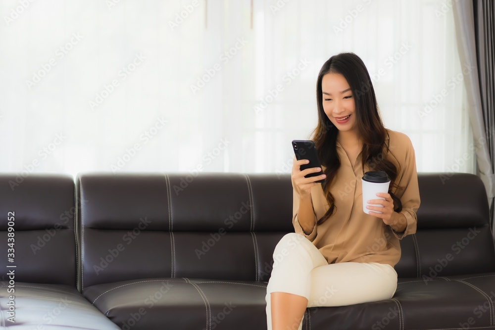 Portrait beautiful young asian woman use mobile smartphone or cellphone with coffee cup on sofa living room Portrait beautiful young asian woman use mobile smartphone or cellphone with coffee cup on sofa living room