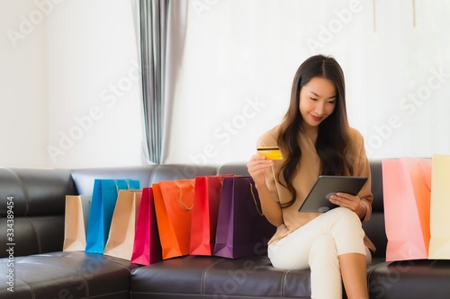 Portrait beautiful young asian woman online shopping with credit card and smartphone around shopping bag © siraphol