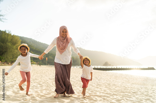 Asian kids having leisure time with their mother at the beach.