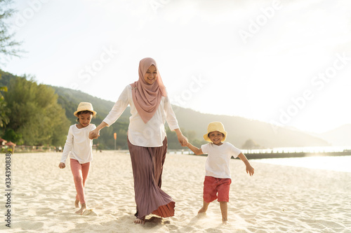Asian kids having leisure time with their mother at the beach.