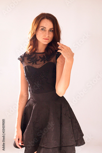stunning portrait of a sexy young brunette girl in a black dress standing. Beauty and Fashion