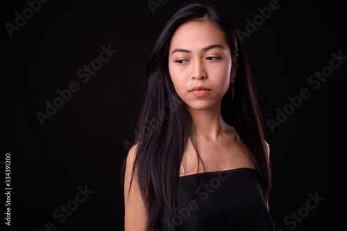 Face of young beautiful Asian woman thinking and looking down